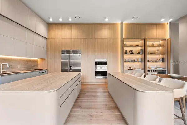 a large open kitchen with kitchen island a large counter top a sink a stove and a refrigerator