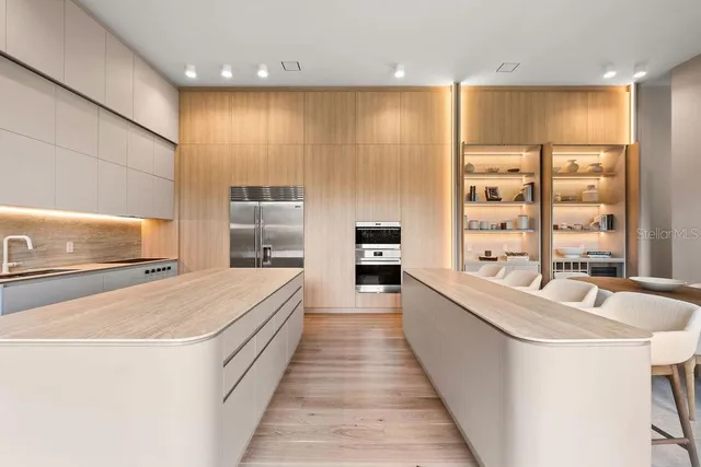 a large open kitchen with kitchen island a large counter top a sink a stove and a refrigerator