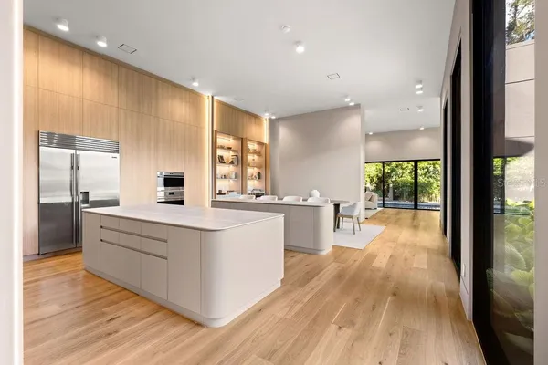 a large kitchen with stainless steel appliances a large counter top a stove and a large window