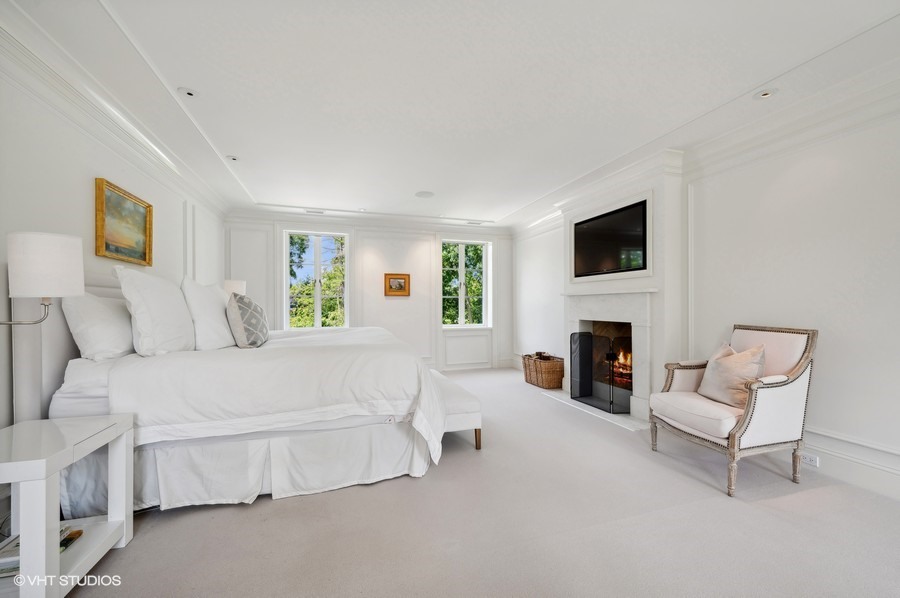 40 Woodley Road Winnetka, IL 60093 - Photo 37 of 60 a spacious bedroom with a bed and a fireplace