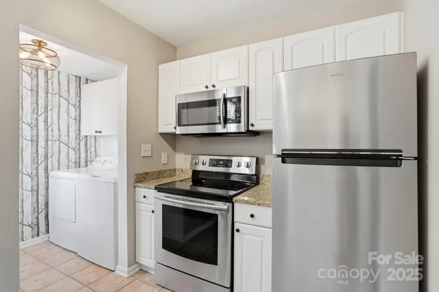 a kitchen with stainless steel appliances white cabinets white stove a microwave and a refrigerator
