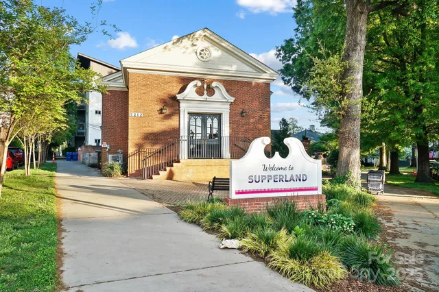 a view of a house with a small yard plants and large tree