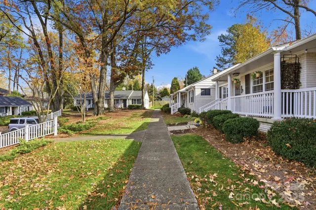 a view of a brick house with a big yard and large trees