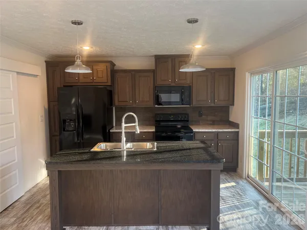 a kitchen with kitchen island granite countertop a stove and a sink