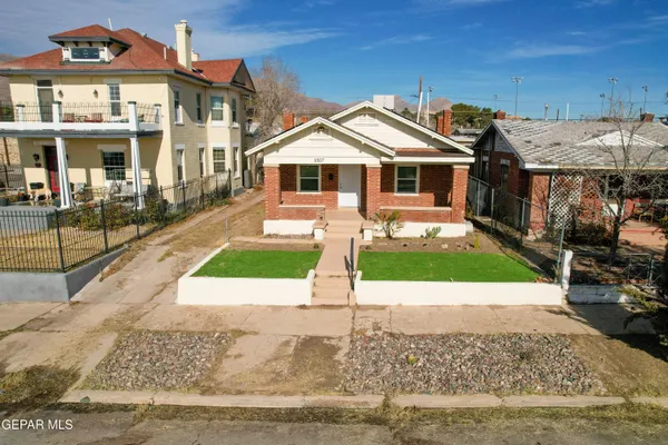a view of a white house with a small yard and large trees