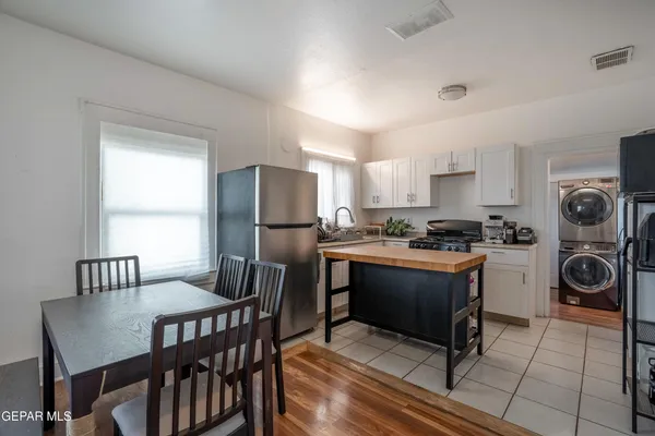 a kitchen with granite countertop a table chairs a sink dishwasher refrigerator and cabinets