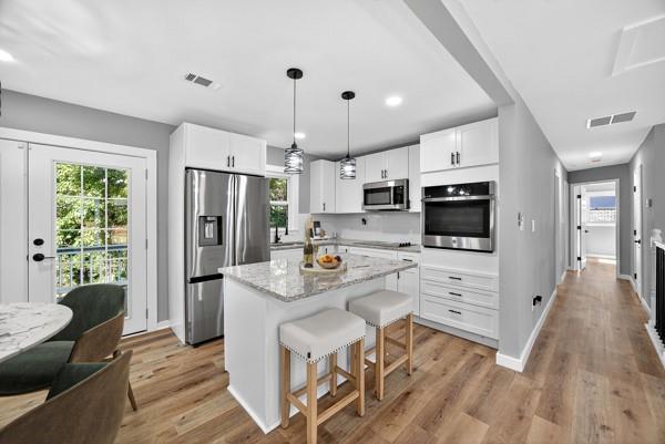 1864 Glen Echo Drive Decatur, GA 30032 - Photo 9 of 38 a kitchen with stainless steel appliances a stove a refrigerator a sink dishwasher and white cabinets with wooden floor