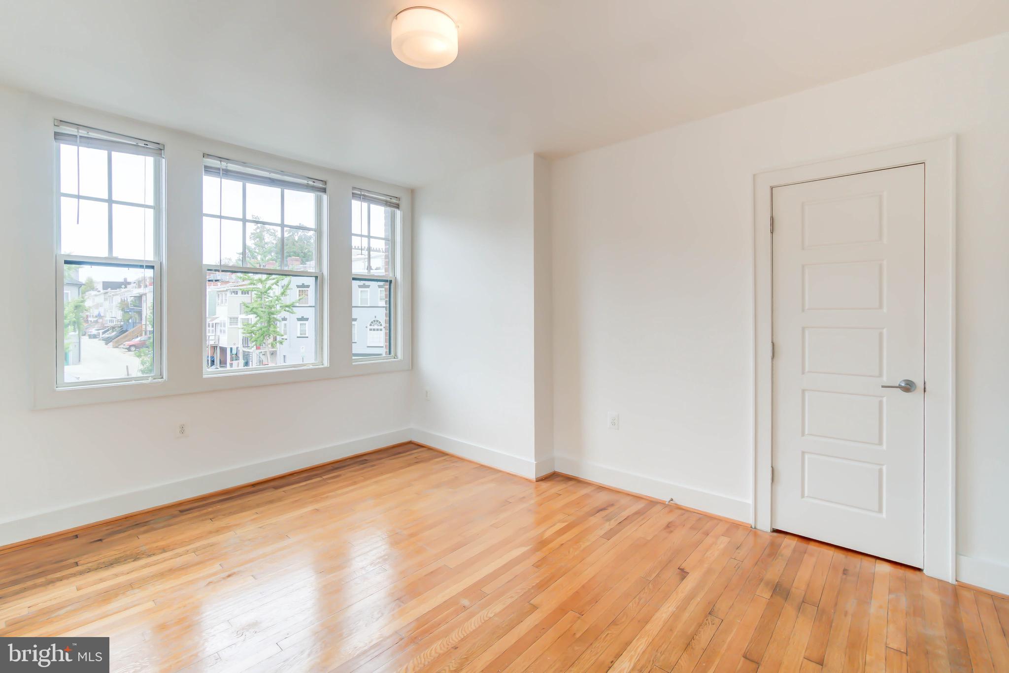 1575 Spring Place Northwest, Unit 35 Washington, DC 20010 - Photo 11 of 22 an empty room with wooden floor and windows