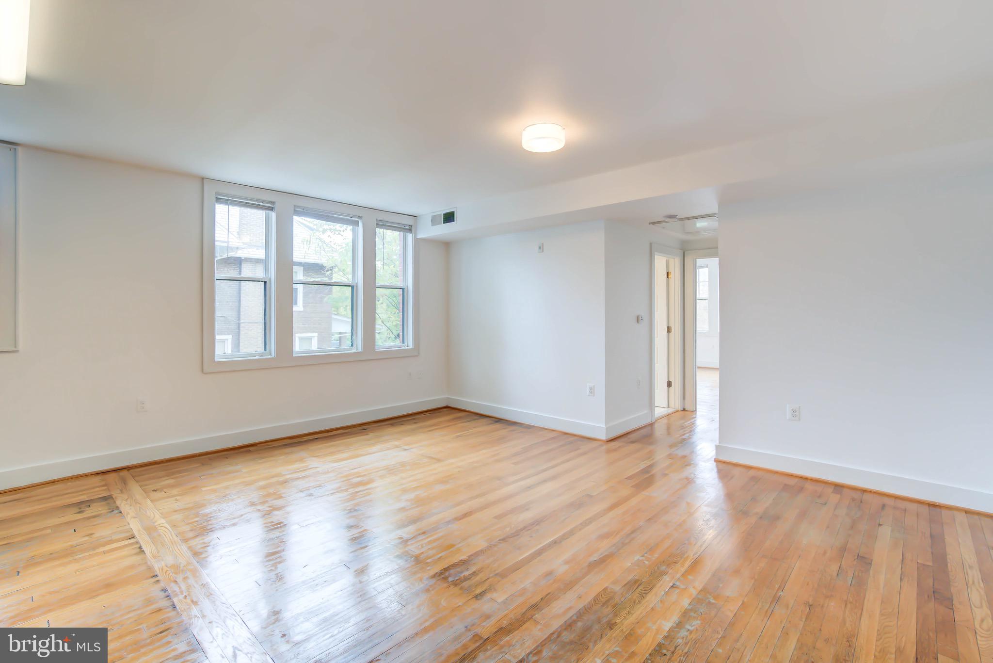 1575 Spring Place Northwest, Unit 35 Washington, DC 20010 - Photo 2 of 22 an empty room with wooden floor and windows