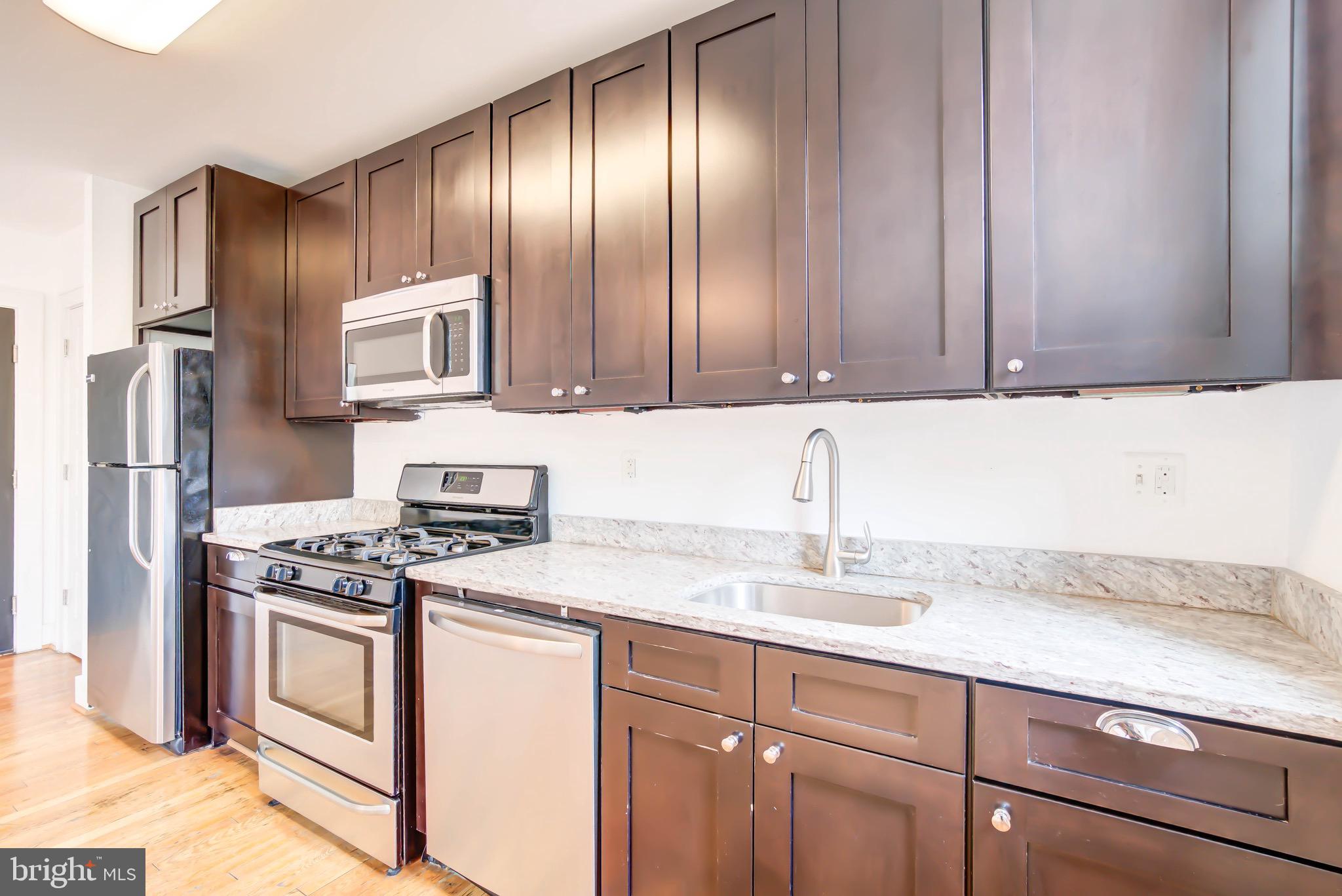 1575 Spring Place Northwest, Unit 35 Washington, DC 20010 - Photo 6 of 22 a kitchen with granite countertop stainless steel appliances a stove a sink and a refrigerator