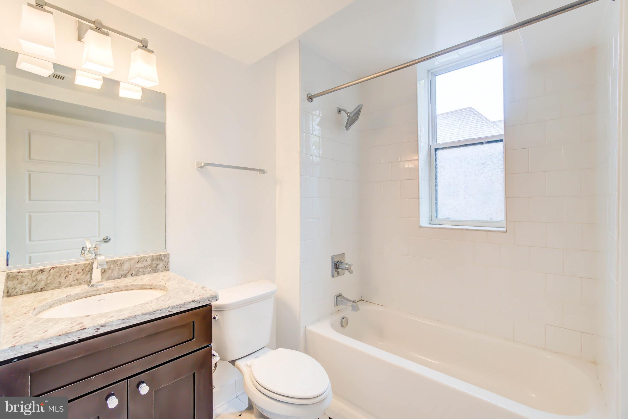 1575 Spring Place Northwest, Unit 35 Washington, DC 20010 - Photo 9 of 22 a bathroom with a granite countertop bathtub shower sink vanity and toilet