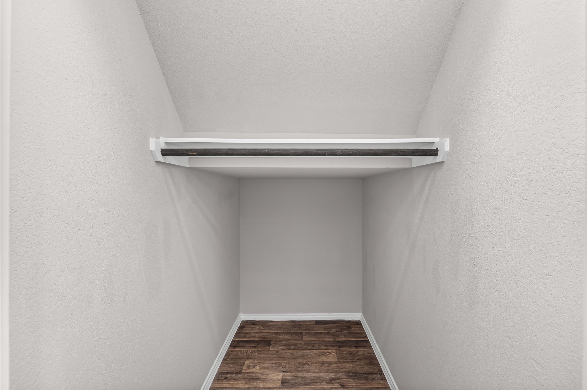 23522 Wedgewood Cliff Way Spring, TX 77373 - Photo 22 of 30 Under the stairs is a compact walk-in closet with a single hanging rod and sleek white walls, Perfect for organized storage or a cute reading or pet nook.