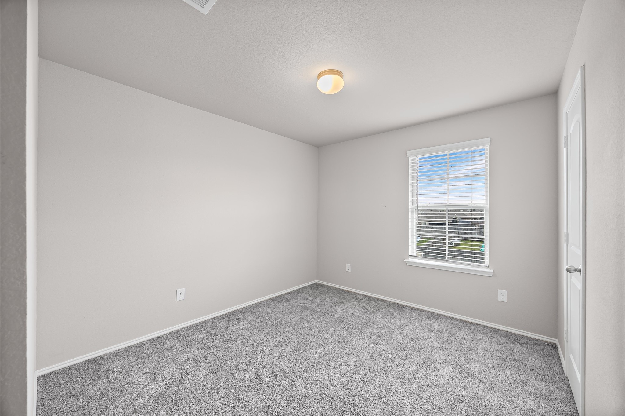 23522 Wedgewood Cliff Way Spring, TX 77373 - Photo 24 of 30 This photo shows a bright, empty room with neutral-colored walls and soft carpeting. It features a window allowing natural light to fill the space, and a simple ceiling light fixture. Ideal as a bedroom or office.