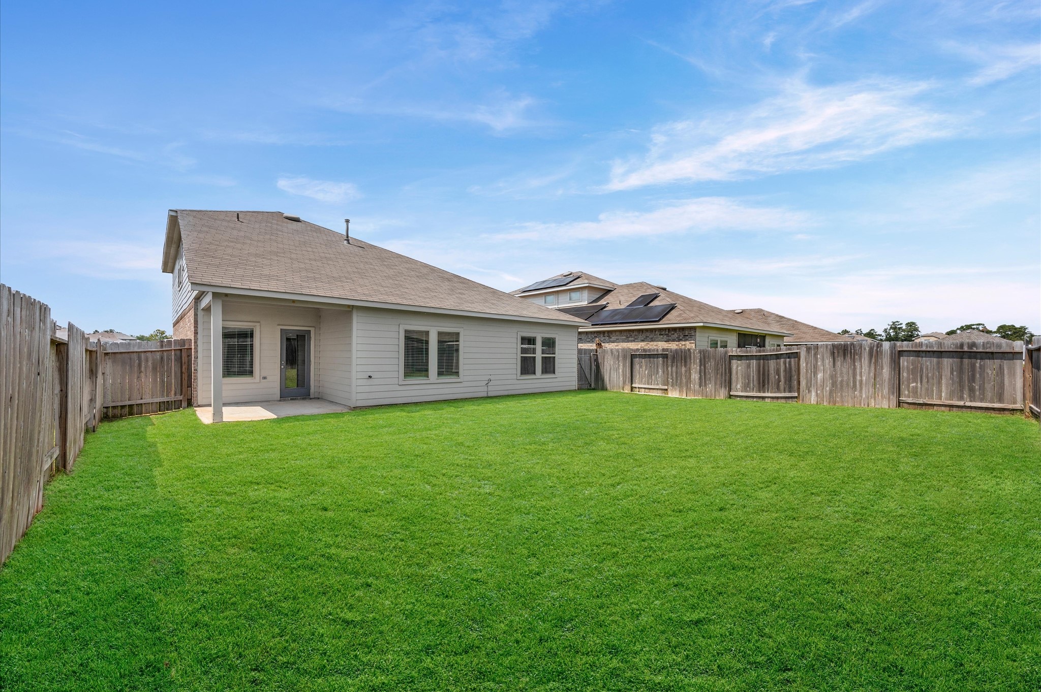 23522 Wedgewood Cliff Way Spring, TX 77373 - Photo 29 of 30 Spacious backyard with well-maintained grass, surrounded by a wooden fence for privacy. The house features a covered patio area, ideal for outdoor relaxation.