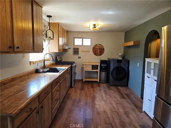 a kitchen with stainless steel appliances granite countertop a refrigerator a stove and a wooden floors