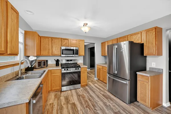 a kitchen with granite countertop a refrigerator a sink dishwasher stove top oven and wooden floor