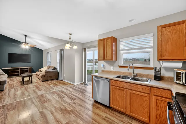 a living room with couches and kitchen view with wooden floor