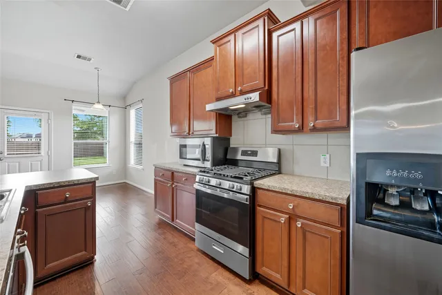a kitchen with stainless steel appliances granite countertop wooden cabinets stove top oven and sink