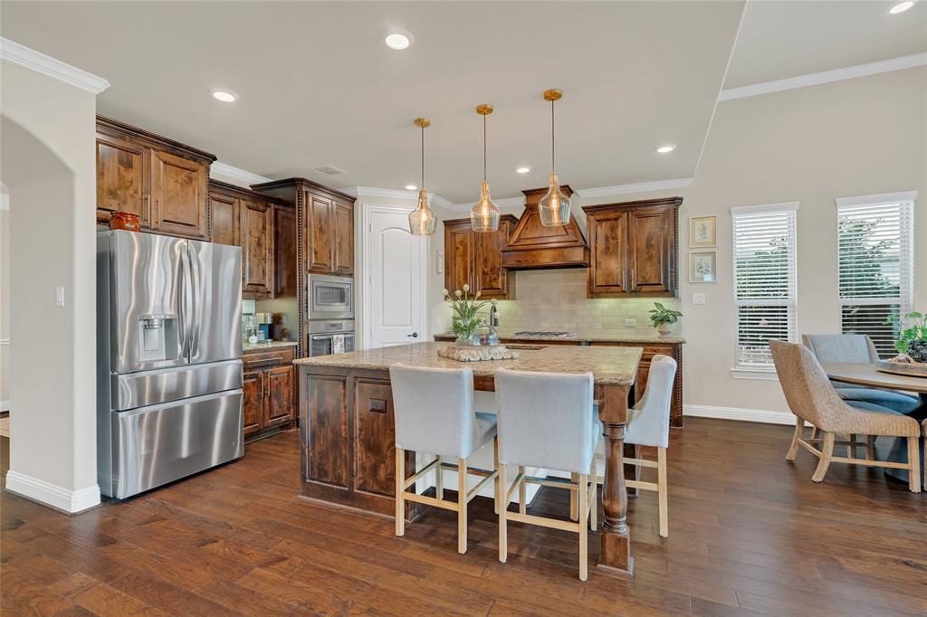 2852 Exeter Drive Trophy Club, TX 76262 - Photo 12 of 40 a kitchen with stainless steel appliances kitchen island granite countertop a refrigerator a stove a dining table and chairs with wooden floor