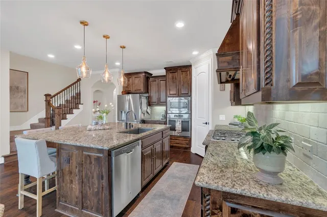 a kitchen with stainless steel appliances granite countertop a kitchen island a stove and a sink