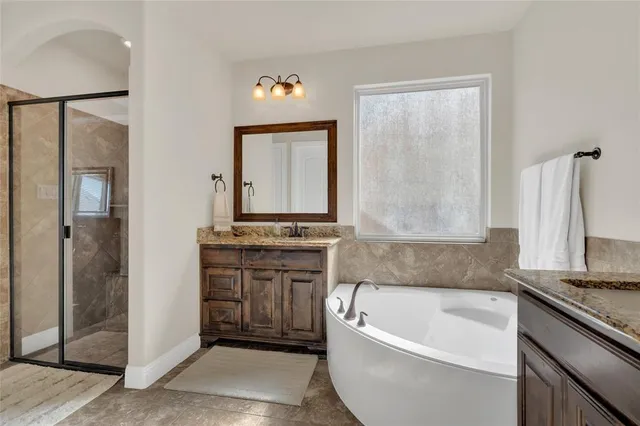 a en suite bathroom with a double vanity sink a mirror a bathtub and shower