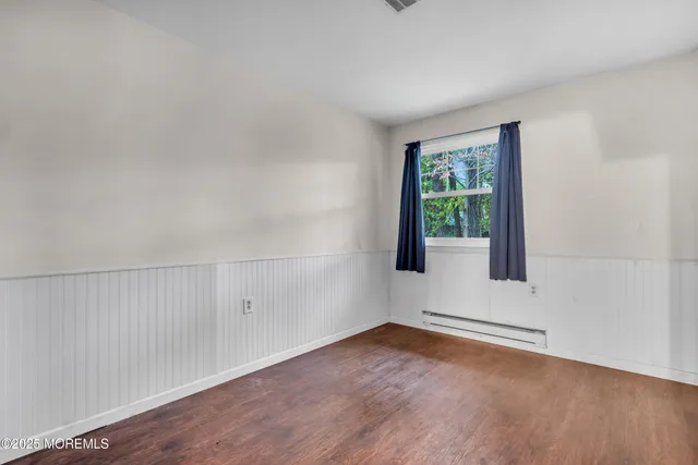 a view of an empty room with wooden floor and windows