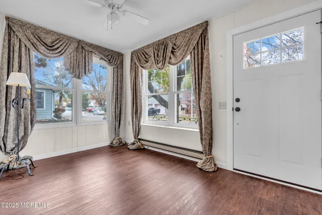 a view of an empty room with a window and wooden floor
