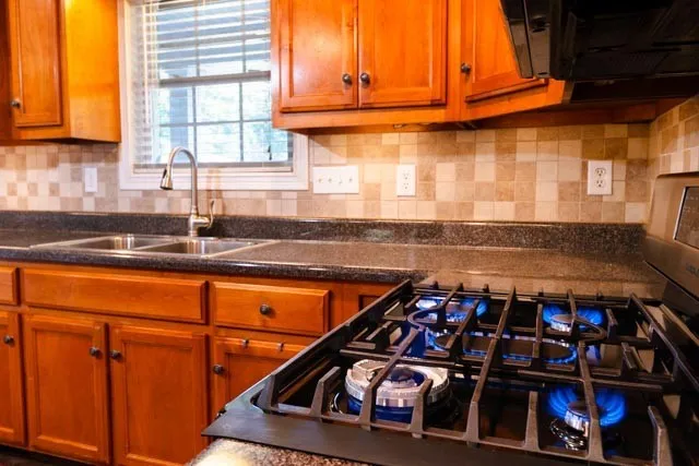 a kitchen with stainless steel appliances granite countertop a stove a sink and a microwave