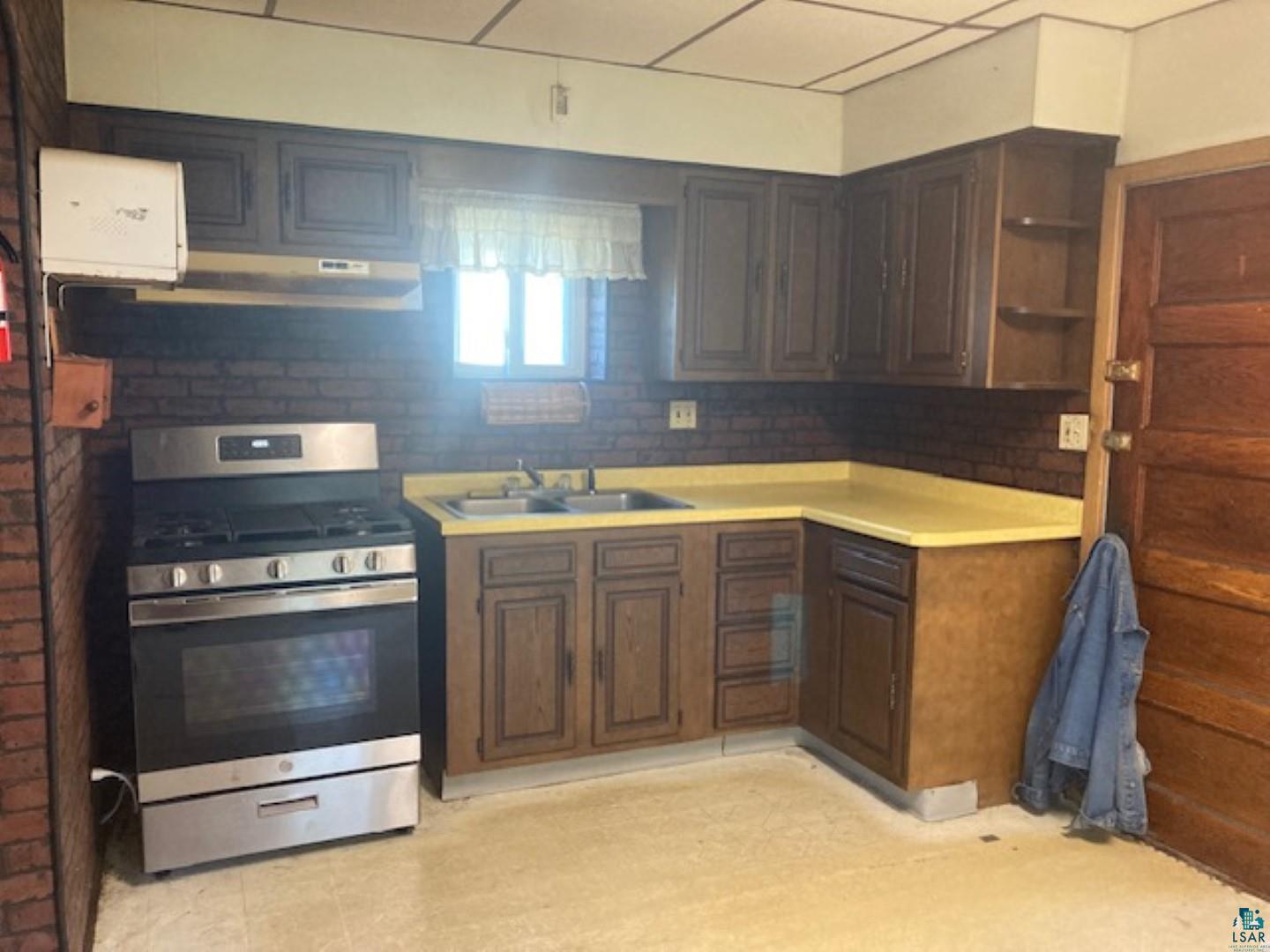 3729 West 2nd Street Duluth, MN 55807 - Photo 9 of 29 Kitchen with backsplash, light tile patterned floors, stainless steel stove, dark brown cabinets, and sink