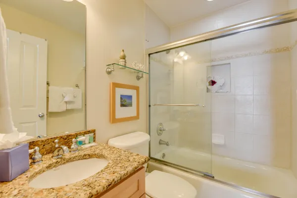 a bathroom with a granite countertop tub sink toilet and shower