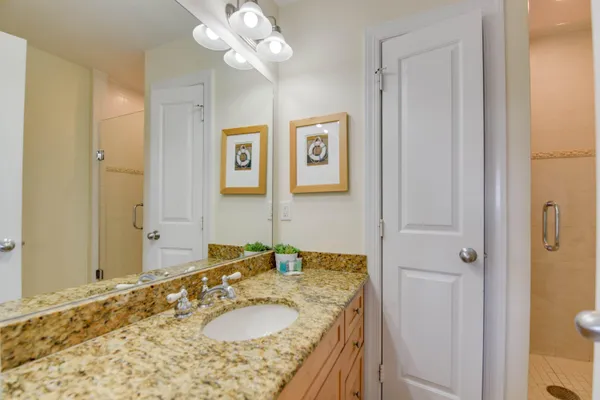 a bathroom with a granite countertop sink a mirror and a shower