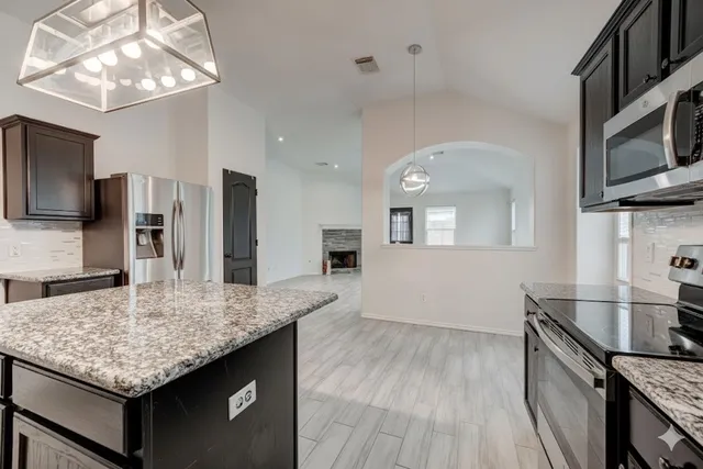 a kitchen with stainless steel appliances granite countertop a kitchen island hardwood floor sink and stove
