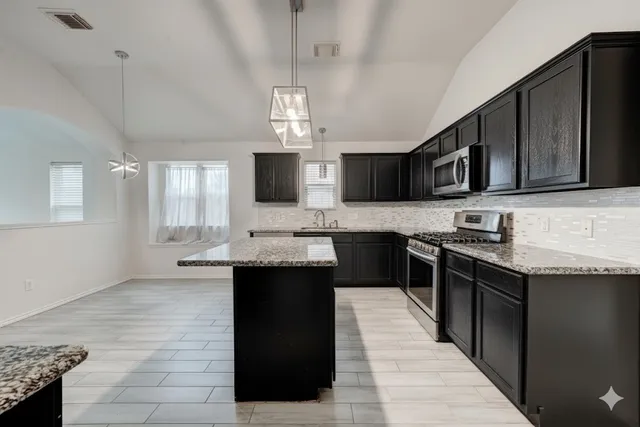a kitchen with stainless steel appliances granite countertop a sink stove and microwave