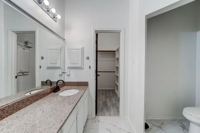 a bathroom with a granite countertop sink a mirror and a toilet