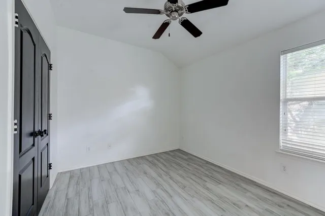 a view of an empty room with a window and wooden floor