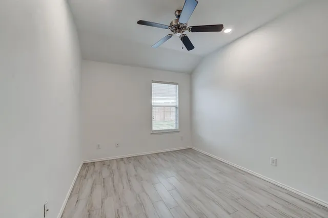 an empty room with a window and ceiling fan