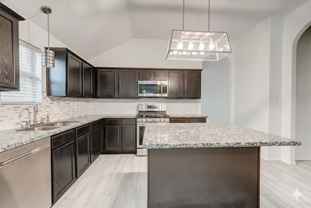 a kitchen with granite countertop stainless steel appliances a stove sink microwave and cabinets