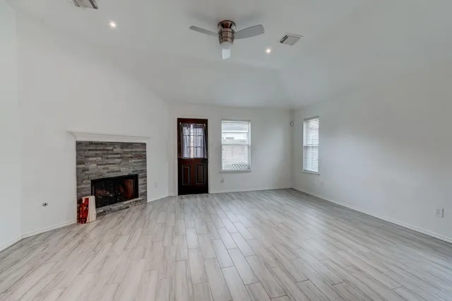 an empty room with windows cabinet and fireplace