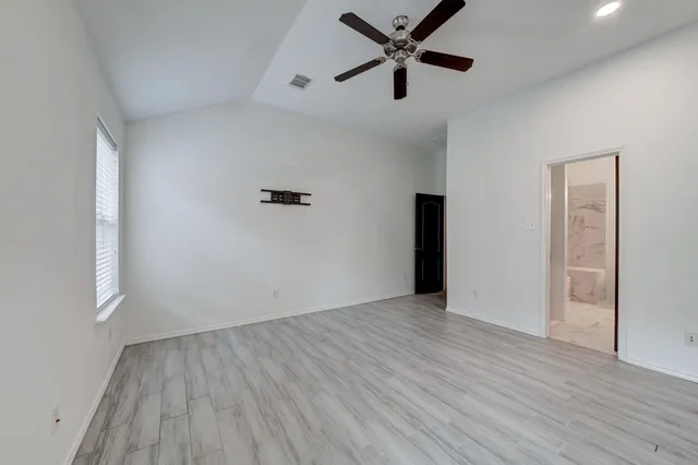 an empty room with wooden floor and a ceiling fan