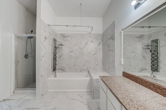 a bathroom with a granite countertop bathtub shower sink and vanity