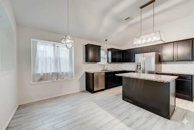 a large kitchen with stainless steel appliances kitchen island granite countertop a sink and a stove