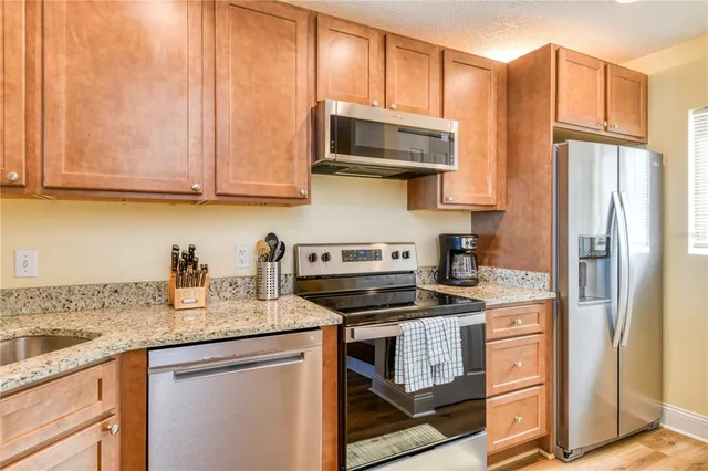 a kitchen with stainless steel appliances granite countertop a refrigerator stove and sink
