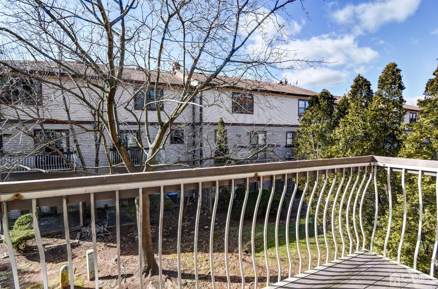 6902 Hana Road Edison, NJ 08817 - Photo 5 of 24 a view of a brick house with large trees and wooden fence