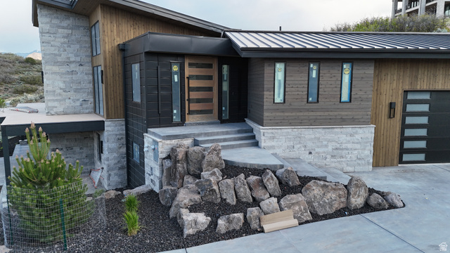 1918 Chimney Rock Road Heber City, UT 84032 - Photo 7 of 74 Contemporary exterior featuring wood-finish siding, stone accents, a standing seam metal roof, a modern garage door with frosted glass panels, and a distinctive front entry door with horizontal wood and frosted glass elements