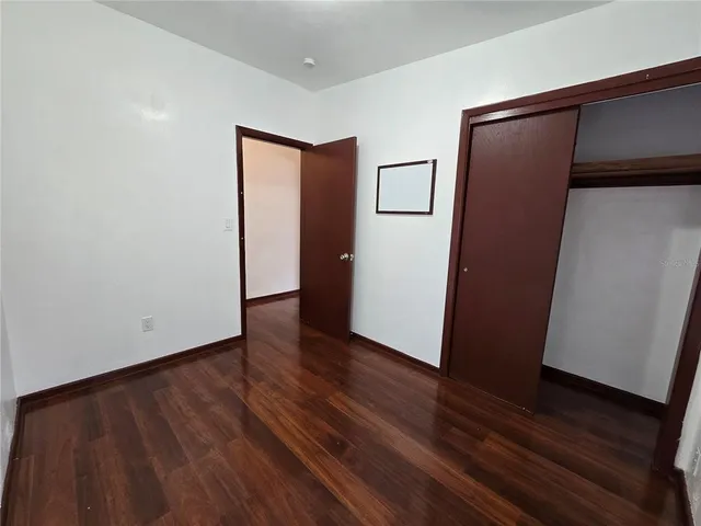 a view of an empty room with wooden floor and door