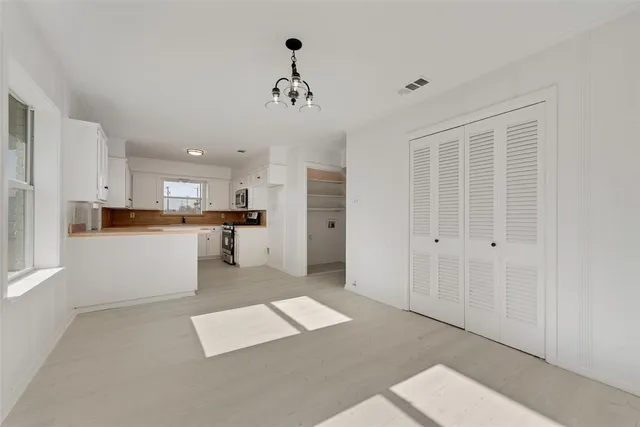 a large white kitchen with kitchen island a sink stainless steel appliances and cabinets