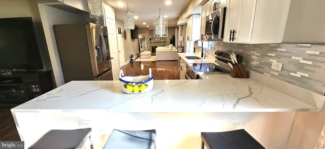 a kitchen with stainless steel appliances kitchen island granite countertop a refrigerator a stove and a sink