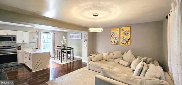 a living room with stainless steel appliances furniture and a kitchen view