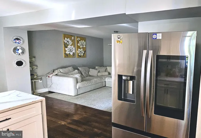 a living room with stainless steel appliances furniture and a refrigerator
