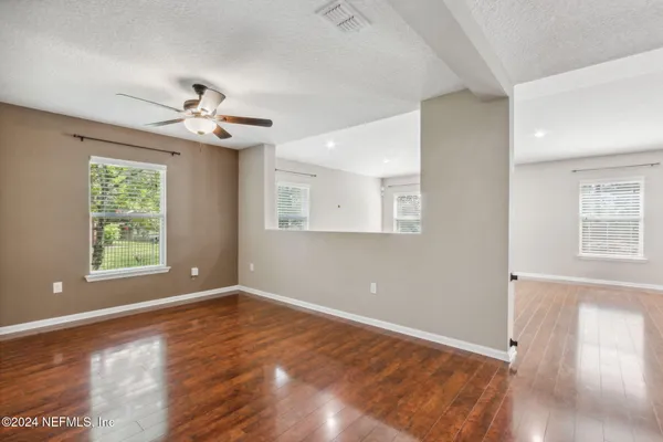 an empty room with wooden floor and windows